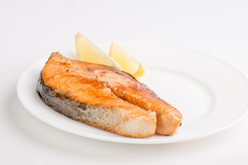 grilled salmon fish steak on a white plate with a place for garnish