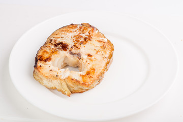 grilled fish steak on a white plate with a place for garnish