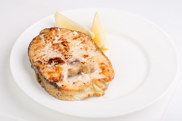 grilled fish steak on a white plate with a place for garnish