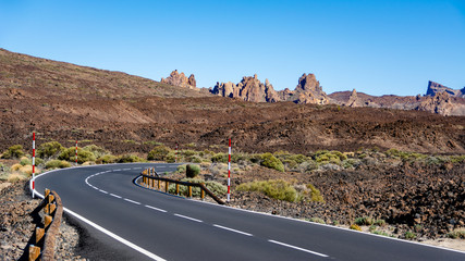 View on stone lava desert and asphalt road in Teide national park. Main landmark of Tenerife island. Popular touristic walking and driving route.