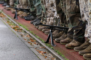 Section of soldiers legs in military uniform and boots standing in line at camp