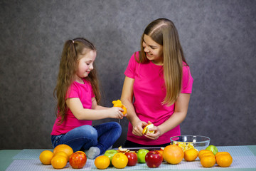daughter and mom cut a fruit salad consisting of apple orange and mandarin