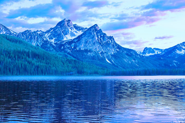 Blue glacial lake with the Sawtooth Mountains jutting up, near Stanley Idaho, USA - obrazy, fototapety, plakaty