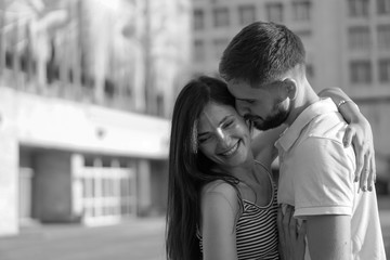 Beautiful couple of man and woman on concrete urban houses background. Romantic theme with a girl and a guy. Spring, summer photo relationship, love, Valentine's day