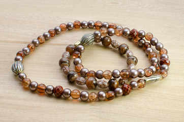Multicolored necklaces with pearls and fancy accessories on wooden background
