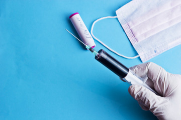 The doctor collects a blood test from a patient. Syringe with blood in the hands of a doctor. Doctor in medical gloves close-up. An outbreak of coronavirus from Wuhan in Asia and Europe. 