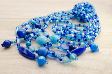 Multicolored necklaces with pearls and fancy accessories on wooden background