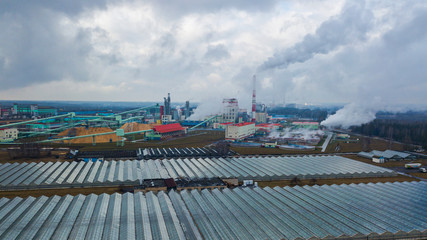 Fototapeta na wymiar Aerial view greenhouse on the background of smoke from the pipes of the pulp mill. Ecological problem concept.