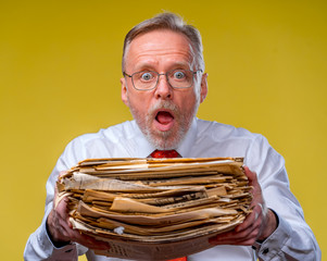 Manager in red tie giving big pile of documents over yellow background, cropped photo.