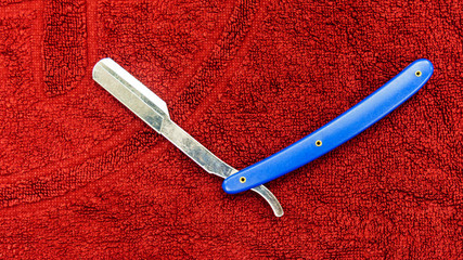 Close-up sharp straight razor on red towel. Vintage razor. Barbershop concept.