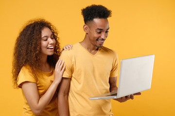Funny young friends couple african american guy girl in casual clothes isolated on yellow orange...