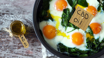 Selective focus. The inscription cbd oil in food. Spinach eggs with cannabis oil. CDB use of oil concept.