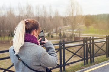 girl takes pictures of nature in the park
