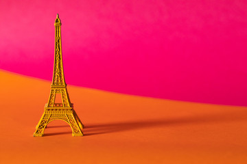 Miniature yellow Eiffel Tower on colorful background, travel and tourism concept. "PARIS" written on it.