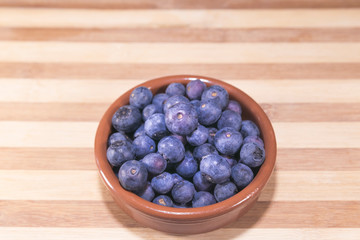 arandanos en cuenco de barro sobre madera