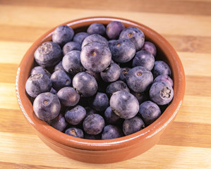 arandanos en cuenco de barro sobre madera