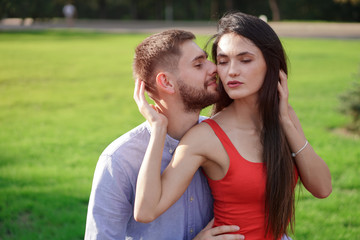 Beautiful couple of man and woman sitting on a bench in a park. Romantic theme with a girl and a guy. Spring Summer theme  relationship, love, Valentine's day