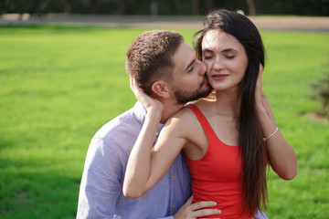 Beautiful couple of man and woman sitting on a bench in a park. Romantic theme with a girl and a guy. Spring Summer theme  relationship, love, Valentine's day