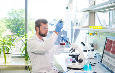 Scientist working in lab. Doctor making microbiology research. Laboratory tools: microscope, test...