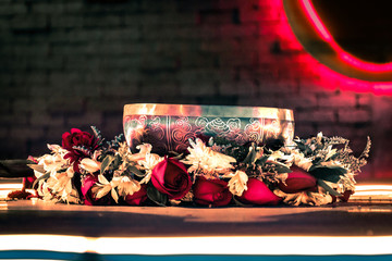 Cuenco Tibetano sobre una cama de flores y luces de fondo