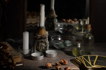 Magic concept. Burning candles and tincture bottles are reflected in old mirror