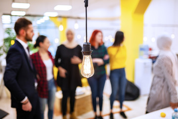 Group of successful business colleagues having a meeting in an office. Decorative modern light bulb...