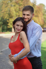 Fototapeta premium Beautiful couple of man and woman against the backdrop of a beautiful park and city architecture. Romantic theme with a girl and a guy. Spring Summer picture relationship, love, Valentine's day