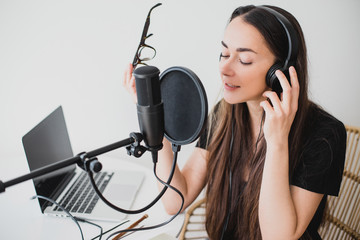 Woman blogger recording radio podcast in studio.
