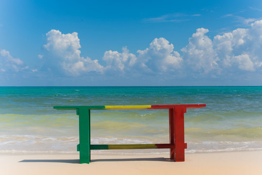 Reggae colors Wood Bench with Caribbean beach background