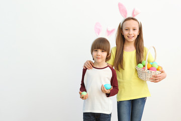 Obraz na płótnie Canvas Cute little boy and girl in rabbit ears and with an Easter basket on a colored background. Easter background with place to insert text. Family Easter traditions.