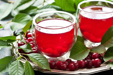 Fresh cherry juice in  glass, cherry berries with leaves