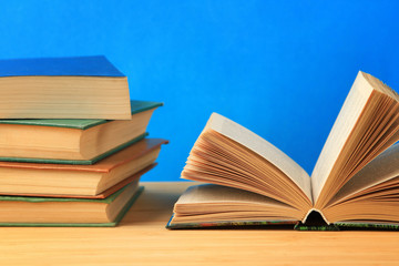 Open antique book on wooden table on wall background