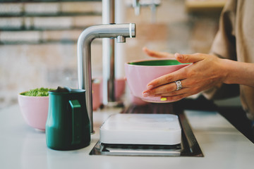 Asian tea ceremony process. Barista's hands holding a pink bowl with freshly whipped matcha powder on a blurred background og a modern vegetarian coffee shop. Making traditional japanese matcha tea.
