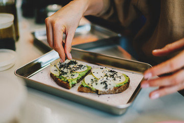 Chef adding pumpkin seeds to delicious vegetarian sandwiches for the breakfast. Healthy and tasty gluten free food. Cooking using natural ingredients.Simple food cooking using avocado and rye bread