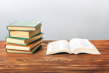 Open book on the table with other books on a gray background.