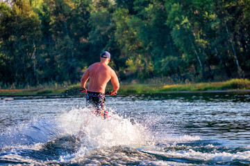 Young man riding water scooter at sea lake river on summer day.