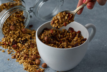 Homemade granola from mix of oat cereals  with dry fruits, nuts and seeds on a grey  concrete table concept of healthy breakfast. Slow living