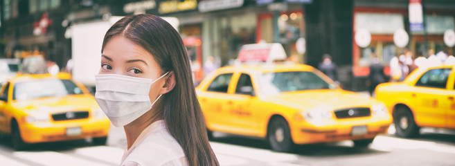 Corona virus travel ban China woman tourist walking in New York city street wearing surgical mask...