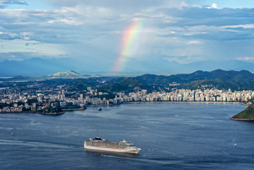 Naklejka na ściany i meble A cruise sailing in Rio de Janeiro with a rainbow on the background, Brazil
