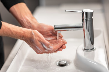 Washing hands man rinsing soap with running water at sink, Coronavirus prevention hand hygiene. Corona Virus pandemic protection by cleaning hands frequently. - obrazy, fototapety, plakaty