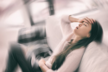 Sick woman with headache feeling faint vertigo holding head in pain with fever and migraine. Blurry motion blur background.