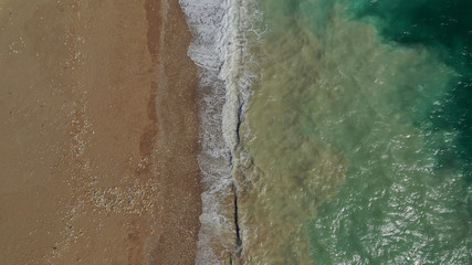 Fototapeta na wymiar Aerial drone top view photo of emerald waves reaching sandy open ocean shore