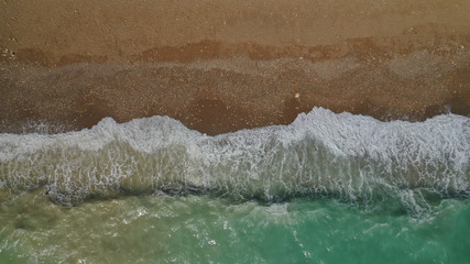 Fototapeta na wymiar Aerial drone top view photo of emerald waves reaching sandy open ocean shore