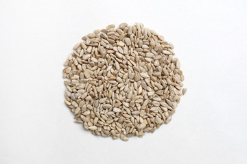 peeled sunflower seeds in circle on white background from above