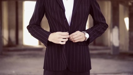 unrecognizable woman in pantsuit fastens a button on a jacket