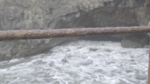 Slow-mo of old rusty railing and water 