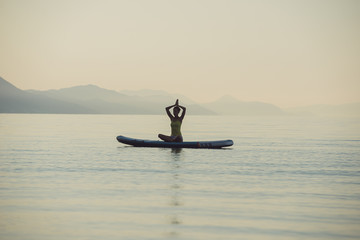 Young woman making a yoga asana position with her hands joined above her head