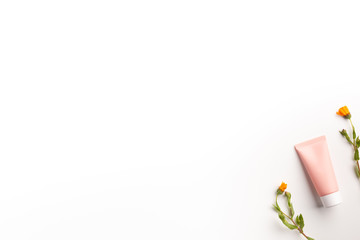 Organic cosmetic concept. Flowers of calendula and tube of cream isolated, on white background. Flat lay, top view, copy space.