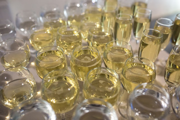 lot of blurred glasses with champagne on the reception party table on light background