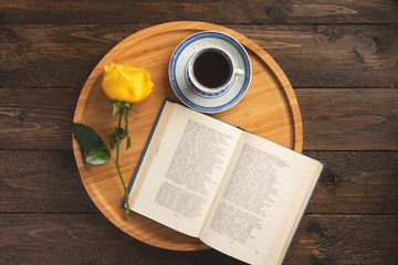 Romantic breakfast. Wooden tray with book, rose, cup of coffee, on wooden background. Flat lay, top view, copy space.